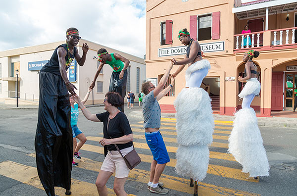 Tourists dancing with stilt walkers in the street